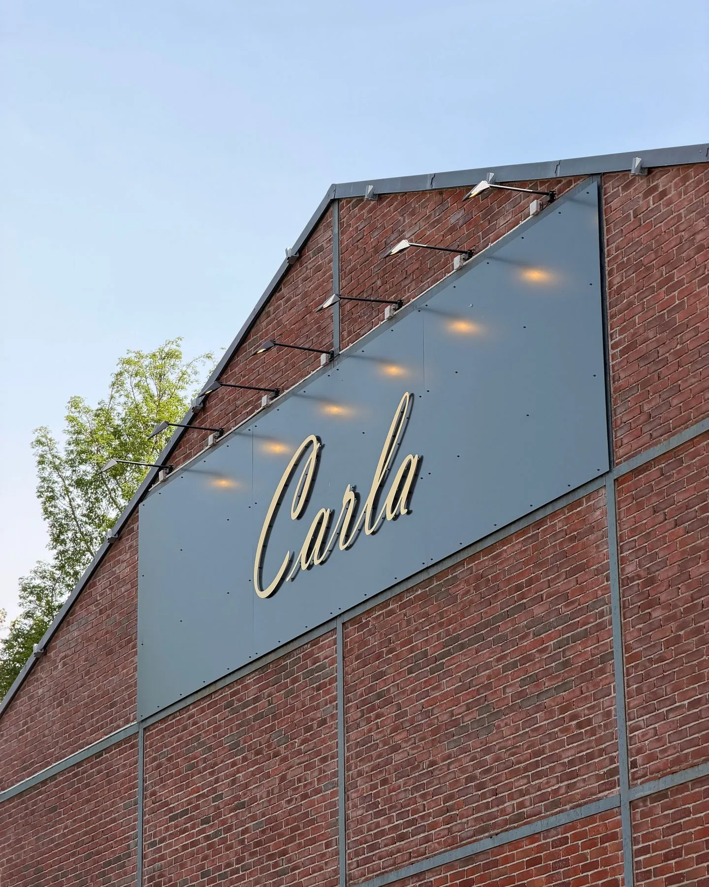Enseigne Carla en lettres lumineuses dorées sur la façade en briques rouges du restaurant, sur les quais de Rouen